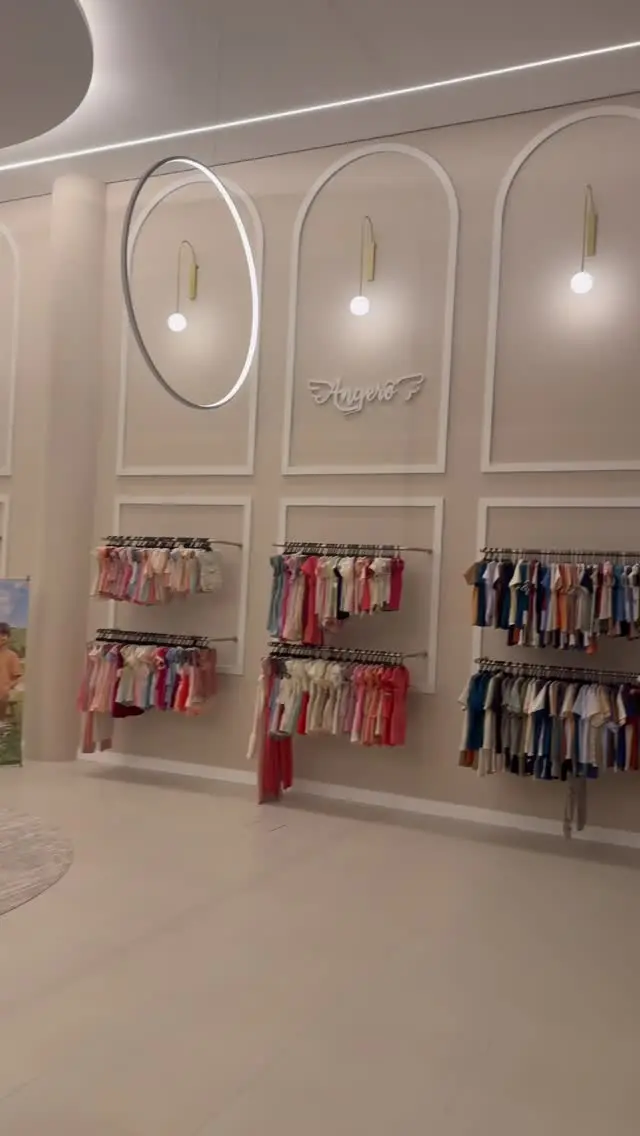 Araras com roupas infantis coloridas sob os arcos do showroom